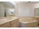 Bathroom with double sinks, corner soaking tub, and light wood cabinets at 1260 Dolphin Bay Way # 203, Sarasota, FL 34242