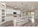 Bright kitchen features white cabinetry, large island, modern appliances, stylish lighting, and open access to a dining area at 2352 Marton Oak Blvd, North Port, FL 34289