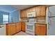 Bright kitchen featuring granite countertops, wooden cabinets, and white appliances at 4751 Travini Circle # 4-116, Sarasota, FL 34235