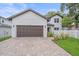 Charming two-story home featuring a two-car garage, brick driveway, landscaped yard, and a white picket fence at 1807 Robinhood St, Sarasota, FL 34231