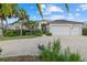 Charming single-story home featuring a three-car garage and lush tropical landscaping at 974 Rotonda Cir, Rotonda West, FL 33947