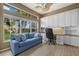 Bright office with a built-in desk, cabinets, a blue sofa and large windows offering views of the lush surroundings at 974 Rotonda Cir, Rotonda West, FL 33947