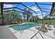 A screened-in pool and patio features ample seating and views of the lush surroundings at 974 Rotonda Cir, Rotonda West, FL 33947