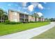 Tan colored building exterior with screened balconies, lush landscaping, and a paved walkway at 811 Fairwaycove Ln # 107, Bradenton, FL 34212