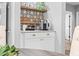 Inviting in-home coffee bar area with white cabinets, rustic shelves, elegant geometric tile backsplash and gold hardware at 807 E Genesee St, Tampa, FL 33603