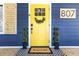 Inviting yellow front door with wreath, potted topiaries, and decorative house number at 807 E Genesee St, Tampa, FL 33603
