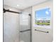 Modern bathroom with frameless shower enclosure and window overlooking lake at 2966 Great Abaco Way, Bradenton, FL 34208
