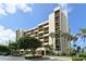 Tan multi-story condominium building with lush landscaping and parking at 1045 Gulf Of Mexico Dr # 403, Longboat Key, FL 34228