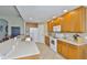 A full kitchen, featuring tiled floors and bright lighting, includes wooden cabinets, a white refrigerator, and white appliances at 11622 Summit Rock Ct, Parrish, FL 34219