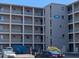 A condominium building with a parking lot showing balconies and a sign, 
