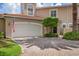 Front view of a tan townhome featuring a white garage door and brick driveway at 1711 Starling Dr # 1711, Sarasota, FL 34231