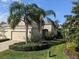 Inviting home exterior featuring a well-manicured lawn, mature trees, and a two-car garage at 4830 Maymont Park Cir, Bradenton, FL 34203