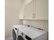 Bright laundry room with washer, dryer, and upper cabinets at 360 N Point Rd, Osprey, FL 34229