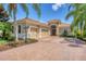 Tan three-car garage home with brick driveway at 14215 Kinglet Ter, Lakewood Ranch, FL 34202