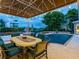 Relaxing poolside patio with dining area and string lights under a covered structure at 815 Tropical Cir, Sarasota, FL 34242