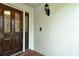 Elegant wood front door featuring decorative glass panels and an adjacent wall-mounted light fixture at 7673 Fairway Woods Dr # 706, Sarasota, FL 34238