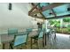 Outdoor kitchen with a long table and seating with an overhead roof structure and a beautiful green view at 7673 Fairway Woods Dr # 706, Sarasota, FL 34238