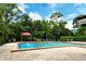 Inviting community pool surrounded by greenery, lounge chairs, and brick patio at 7673 Fairway Woods Dr # 706, Sarasota, FL 34238