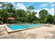 Inviting community pool surrounded by lush greenery, lounge chairs and a brick patio at 7673 Fairway Woods Dr # 706, Sarasota, FL 34238