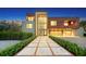 Modern home with brick and wood exterior, double garage, and landscaped walkway at night at 2945 Pyrula Dr, Longboat Key, FL 34228