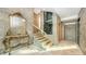 Elegant entryway with glass-railed staircase, ornate console table, and stone tile at 2945 Pyrula Dr, Longboat Key, FL 34228