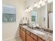 Bathroom featuring double sinks, granite countertops, and a large mirror with decorative lighting at 13215 Ramblewood Trl, Bradenton, FL 34211