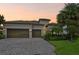 Charming home boasts a tile roof, two-car garage, and a brick driveway, complemented by lush landscaping at 13215 Ramblewood Trl, Bradenton, FL 34211