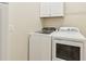 Bright laundry room featuring a white front-load washer and dryer, with storage cabinets above at 13215 Ramblewood Trl, Bradenton, FL 34211