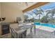 Covered outdoor dining area featuring a built-in grill and beverage cooler overlooking the screened-in pool at 13215 Ramblewood Trl, Bradenton, FL 34211
