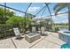 Covered patio with lounge chairs and fire pit overlooking the screened-in pool and lake at 13215 Ramblewood Trl, Bradenton, FL 34211