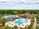 Community pools and clubhouse aerial view, with sun loungers, patio seating, and lush landscaping under a partly cloudy sky at 13215 Palmers Creek Ter, Lakewood Ranch, FL 34202