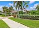 Inviting front yard featuring lush landscaping, palm trees, and a paver walkway leading to the home at 13215 Palmers Creek Ter, Lakewood Ranch, FL 34202