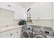 Bright laundry room with white cabinets, modern washer and dryer, sink and plant near a window at 13215 Palmers Creek Ter, Lakewood Ranch, FL 34202