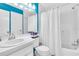 Bright bathroom featuring white fixtures, blue accent wall, and a shower with a white shower curtain at 1602 Stickney Point Rd # 305, Sarasota, FL 34231