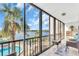 Lanai with floor to ceiling glass doors and railings, showcasing a pool and waterfront view with palm trees at 1602 Stickney Point Rd # 305, Sarasota, FL 34231