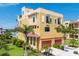 Beautiful yellow three-story home with a red roof, arched windows, palm trees and an attached two car garage at 1450 Silvia Shores Dr, Apollo Beach, FL 33572