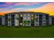 Exterior view of condo building at sunset, featuring well-lit balconies and lush landscaping at 17704 Gawthrop Dr # 402, Bradenton, FL 34211
