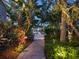 Lighted pathway meanders through tropical landscaping toward a patio area at 5727 Riegels Point Rd, Sarasota, FL 34242