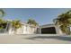 Modern home exterior with white walls, dark garage door, and palm trees at 18770 Mcgrath Cir, Port Charlotte, FL 33948