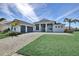 Charming home exterior featuring lush green lawn, palm trees, and a brick-paved driveway at 17938 Palmiste Dr, Bradenton, FL 34202