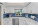 Bright kitchen boasts white cabinets, modern appliances, white countertops, and a blue backsplash at 3705 E Bay Dr # 115, Holmes Beach, FL 34217