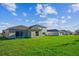 An exterior backyard view displaying a large, lush green lawn with newly built homes and blue skies at 5917 Laurelcrest Gln, Palmetto, FL 34221