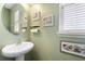 Small bathroom with pedestal sink, framed mirror, and light green walls at 5735 Broad River Run, Ellenton, FL 34222