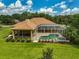 Aerial view of a screened in pool and spa, surrounded by lush greenery and manicured landscaping in the backyard at 14526 17Th E Ave, Bradenton, FL 34212