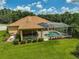 Aerial view of a screened in pool and spa, with an outdoor kitchen and lush green lawn in the backyard at 14526 17Th E Ave, Bradenton, FL 34212