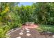 Relaxing backyard patio with wood table and chairs, surrounded by tropical landscaping at 839 40Th St, Sarasota, FL 34234