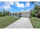 White single-story house with gray roof, driveway, and landscaped lawn at 221 Evergreen St, Punta Gorda, FL 33982