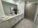 Modern bathroom featuring a double vanity with quartz countertops and a tiled walk-in shower at 17445 Opal Sand Dr # 104, Venice, FL 34293