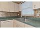 Kitchen with double sink, green countertops, and tin backsplash at 12405 3Rd E St # 206, Treasure Island, FL 33706