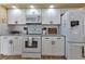 Modern kitchen featuring white appliances, granite countertops, white subway tile backsplash, and sleek black hardware at 13791 Palmetto Point Ct, Port Charlotte, FL 33953